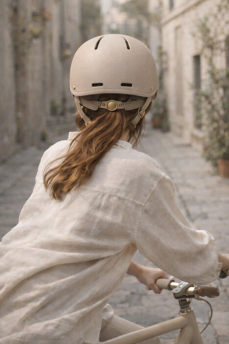 vrouw fietst door smalle straat met Vélune fietshelm Sand - achterzijde met ventilatieopeningen
